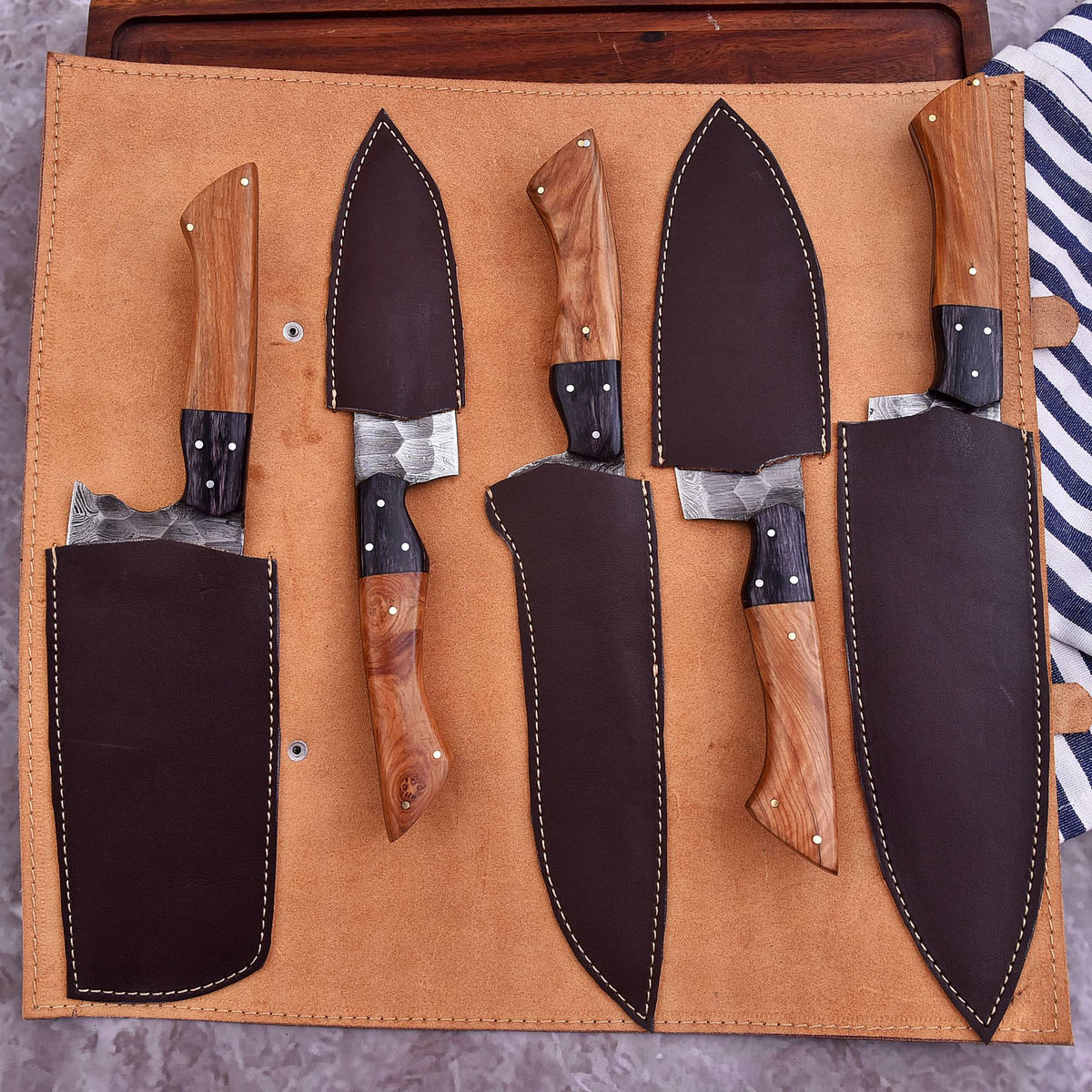 A set of five kitchen knives with wooden handles and dark metal blades, arranged in a tan leather roll-up knife case. The knives have dark brown leather sheaths, with two sheaths partially pulled open to reveal the knives inside.
