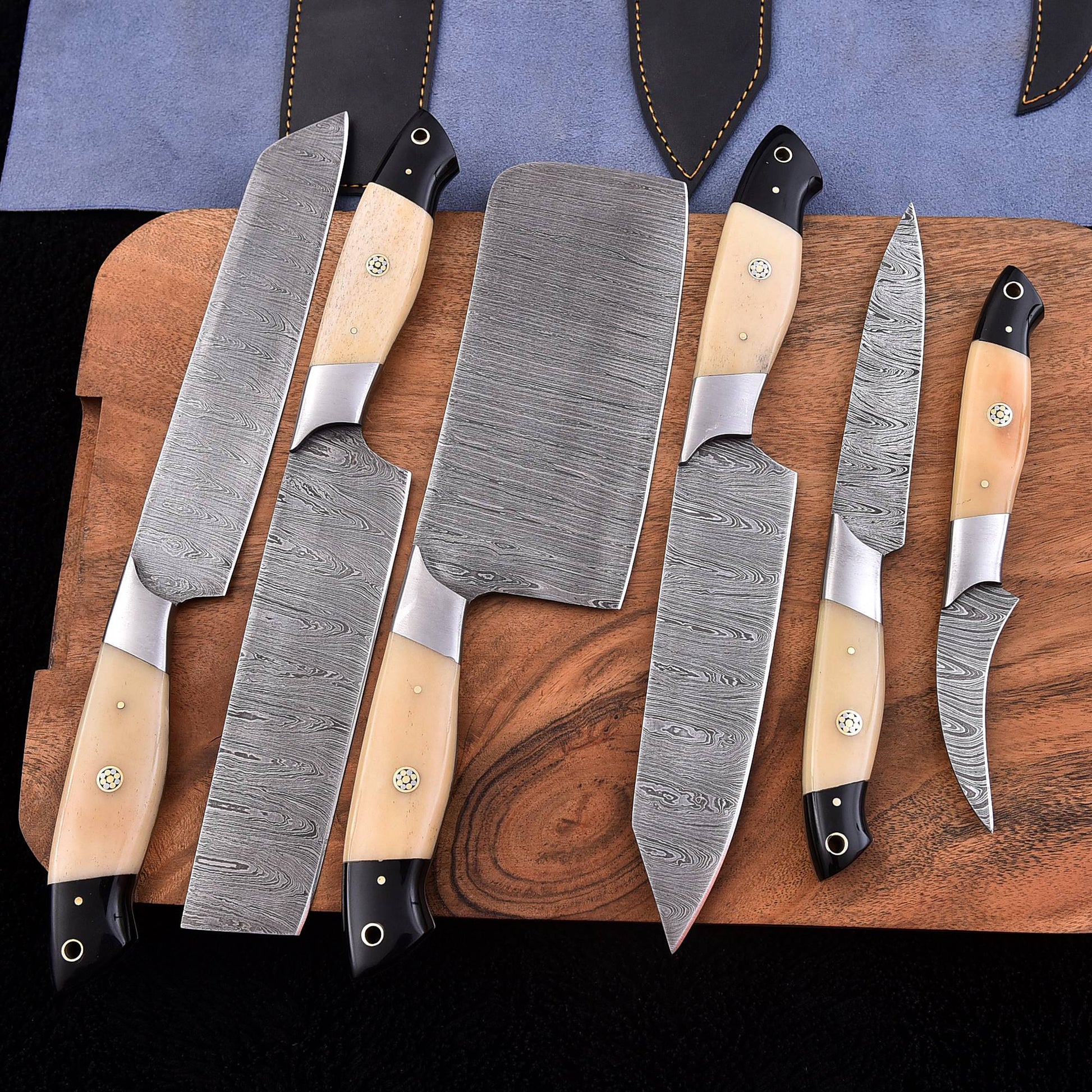 Six-piece handmade Damascus kitchen knife set with light bone and wood handles, including a bread knife, cleaver and chef knives