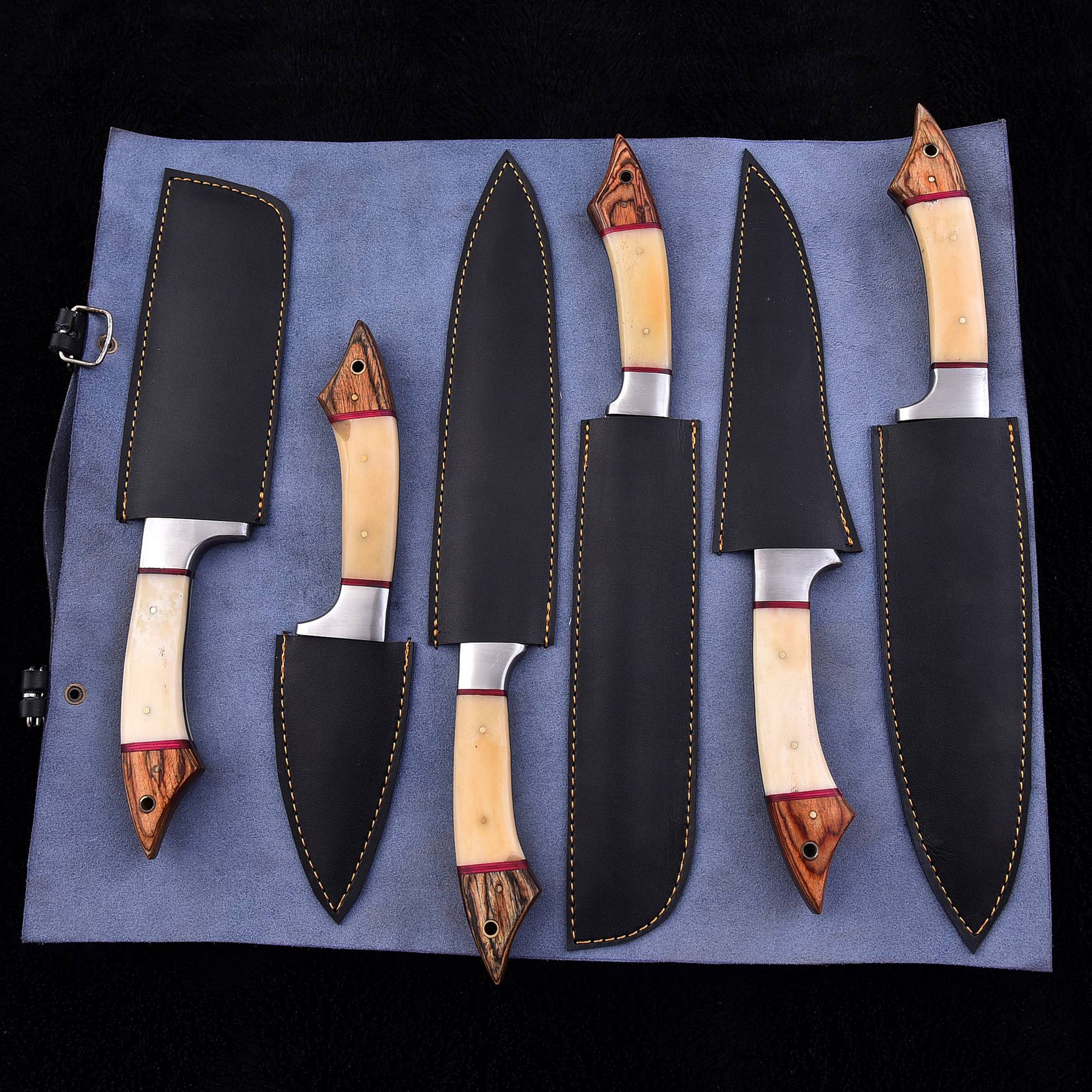 A set of six kitchen knives with cream-colored bone handles and dark wood accents, displayed on a blue fabric roll-up case against a black background.