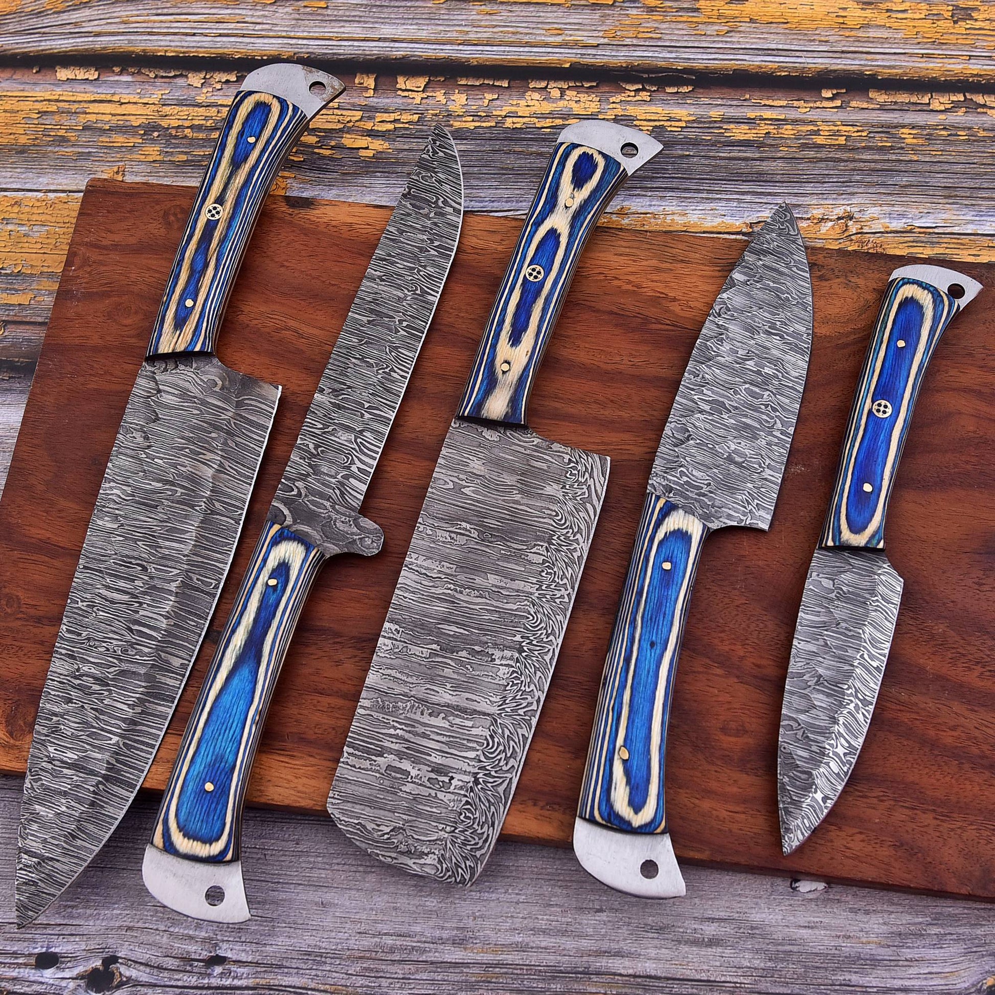 Set of five Damascus knives with blue handles on a wooden surface