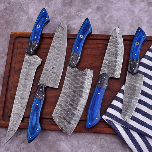 Five-piece handmade Damascus chef knife set with patterned blades and blue wooden handles displayed on a wooden cutting board