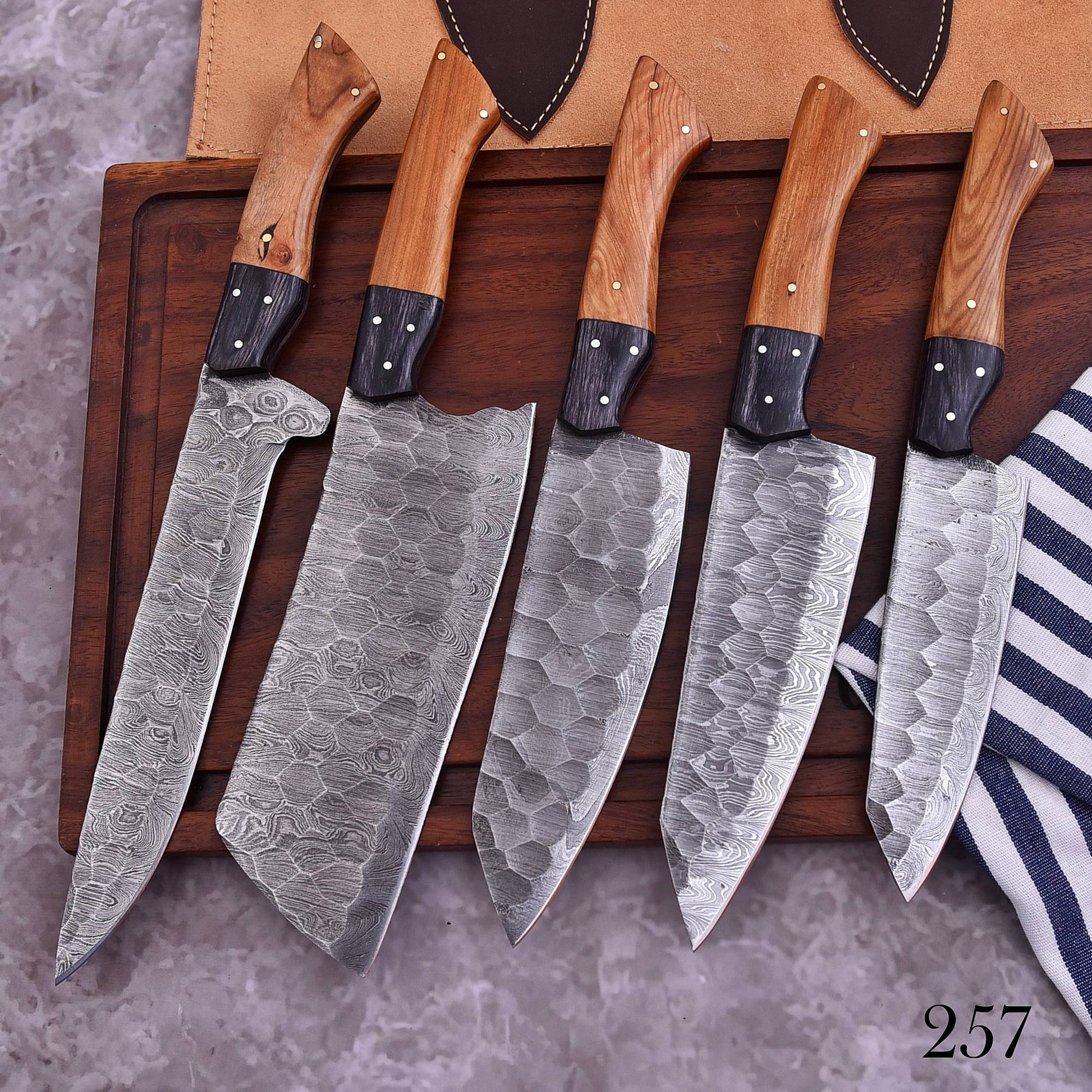 Five-piece handmade Damascus chef knife set with hammered patterned blades and natural two-tone wooden handles