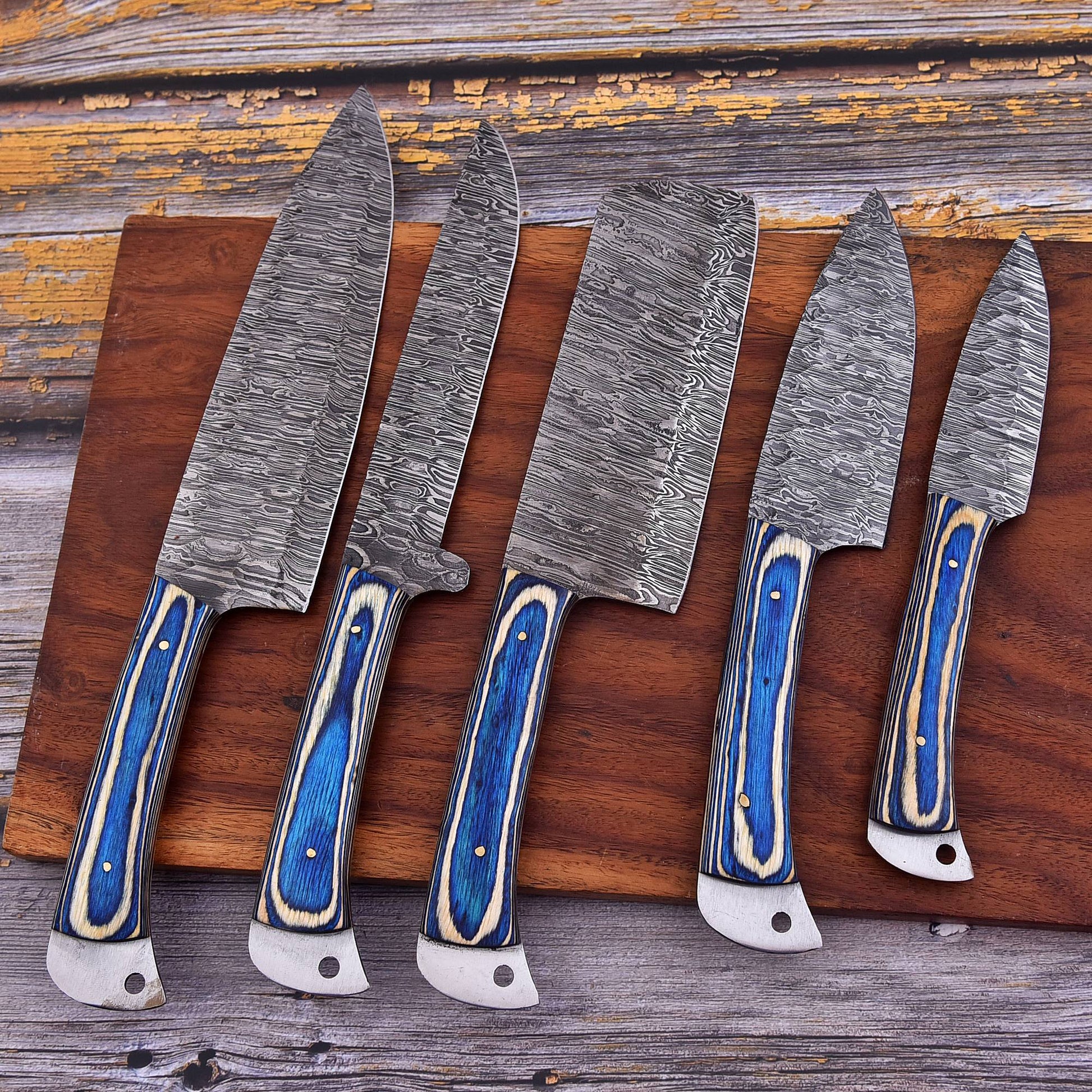 Five kitchen knives with textured steel blades and blue-and-cream striped handles arranged on a wooden cutting board over a rustic weathered wood surface.